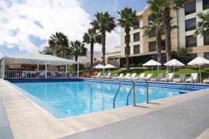 una piscina in un hotel con sedie e ombrelloni di NH Iquique Costa a Iquique