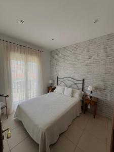 a bedroom with a white bed and a brick wall at Casa Rural El Lio in Ruidera
