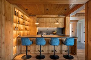 a kitchen with wooden walls and blue bar stools at Solis Thermal Villas- HOT pool in Banya +47 photos
