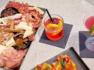 a table topped with plates of food and a drink at TRIBE Milano Malpensa in Vizzola Ticino