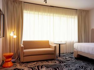 a hotel room with a chair and a bed at TRIBE Milano Malpensa in Vizzola Ticino