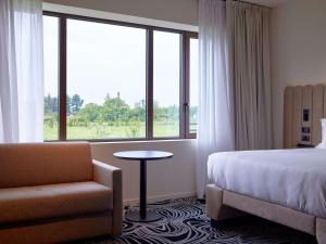 a hotel room with a bed and a chair and a window at TRIBE Milano Malpensa in Vizzola Ticino