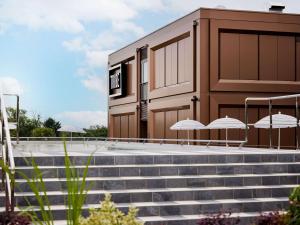 a building with stairs and umbrellas in front of it at TRIBE Milano Malpensa in Vizzola Ticino