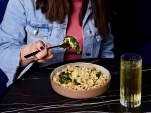 a woman sitting at a table with a bowl of food at TRIBE Milano Malpensa in Vizzola Ticino