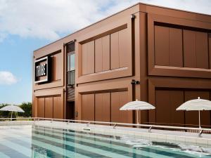 a building with a swimming pool and two umbrellas at TRIBE Milano Malpensa in Vizzola Ticino