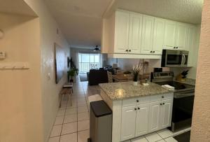 a kitchen with white cabinets and a living room at Siesta Key White Sands Condo in Siesta Key