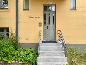 un bâtiment jaune avec des escaliers menant à une porte dans l'établissement Kotimaailma Villa Hortus - Homely Studio for 2, à Turku