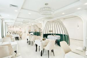 un ristorante con tavoli e sedie bianchi e un lampadario di Grand Resort Pavel Banya Medical and SPA EpiCentrum a Pavel Banya