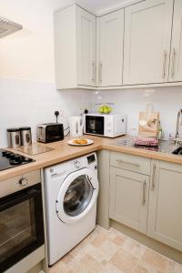 a kitchen with a washing machine and a microwave at Above The Pub in Alvechurch +3 photos