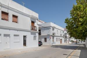 Una calle vacía con edificios blancos y un coche. en Apartamento Maria A, en Vejer de la Frontera