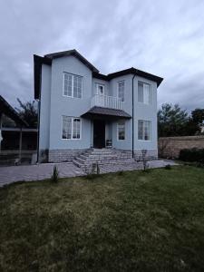 a large white house with a porch on a lawn at Center of Gebele Castel in Gabala