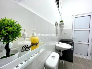 a white bathroom with a toilet and a sink at The Pancarona240 in Seri Iskandar
