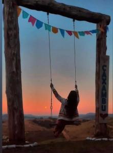 a girl is playing on a swing in a tree at Alvorada Guest House in Caxambu