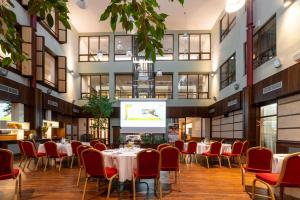 a dining room with tables and chairs and a projection screen at Hotel Baltaci Atrium in Zlín