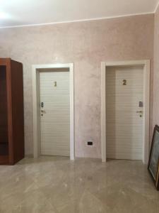 two white doors in a room with a tile floor at Tramonti salentini in San Marzano di San Giuseppe +1 photo