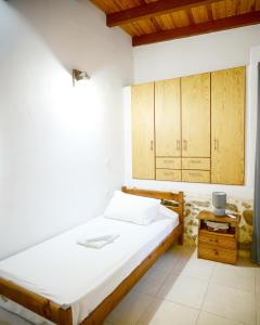 a bedroom with a white bed and wooden cabinets at Guest house Dimitra in Sitia