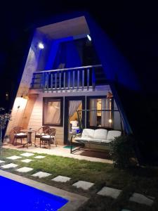 HappyHouse Bungalov Three-Room, SPA JAKUZİ SW POOL with lake view, Sapanca B1 في صبنجة: منزل به أريكة بيضاء على الفناء في الليل