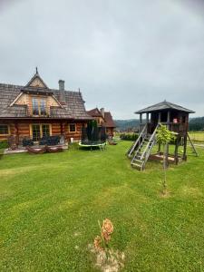 a log house with a playground in the yard at Góralskie przytulne Domki u Kantora 13E in Poronin