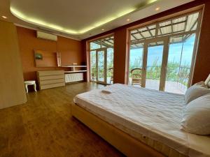 a large bedroom with a large bed and large windows at Dacha U Morya in Odesa