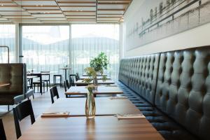 a restaurant with tables and chairs and a large window at Hotel am See in Hard