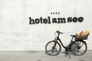 a bike parked next to a wall with a sign at Hotel am See in Hard