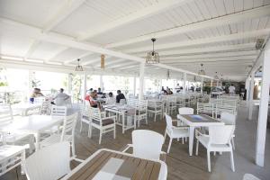 a white restaurant with white tables and white chairs at Hotel Vila Barbaut in Karpen