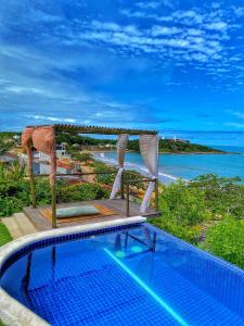 a swimming pool with a canopy and a view of the ocean at Villa Jardim Mar in Anchieta