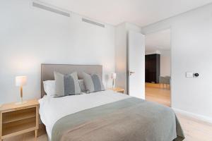 a white bedroom with a large bed with two lamps at Old Cape Quarter 1 Bedroom Units in Cape Town