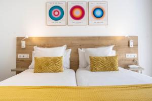 a bedroom with two beds with yellow and white pillows at Hôtel de la Fontaine in Nice