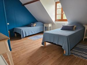 two beds in a room with blue walls and wooden floors at La maison de Jean in Saint-Riquier