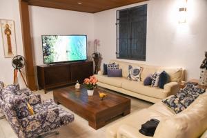 Una sala de estar con sofás y un televisor de pantalla plana. en A Casa Bella - Guesthouse, en Ilhabela