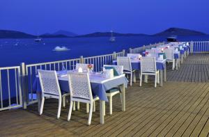 a row of tables and chairs on a deck with the water at Lugga Boutique Hotel & Beach in Ortakent