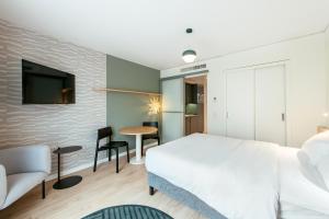 a bedroom with a white bed and a tv on a brick wall at Aparthotel Adagio Muenchen City in Munich