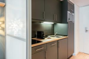 a kitchen with black cabinets and a sink at Aparthotel Adagio Muenchen City in Munich