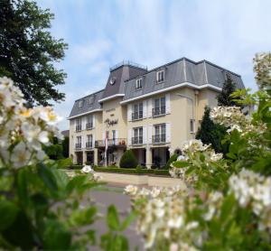 ein großes Gebäude mit weißen Blumen davor in der Unterkunft Romantik Parkhotel het Gulpdal in Slenaken