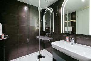 a bathroom with a sink and a glass shower at Aparthotel Adagio Muenchen City in Munich