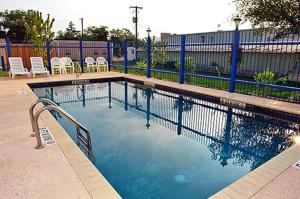 a swimming pool with chairs and a fence at Wine Country Inn in Fredericksburg