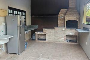 a kitchen with a brick fireplace and a refrigerator at Chácara para Hospedagem e Festa in Taubaté