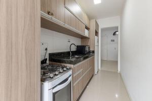 a kitchen with a stove and a counter top at Excelente Apartamento a 2 minutos da Praia de Bombas in Bombas +9 photos