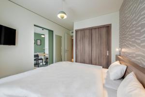 a bedroom with a large white bed and a sliding door at Aparthotel Adagio Muenchen City in Munich