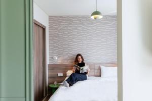 a woman sitting on a bed reading a book at Aparthotel Adagio Muenchen City in Munich