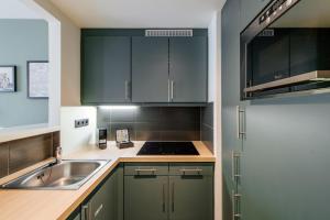 a kitchen with green cabinets and a sink at Aparthotel Adagio Muenchen City in Munich