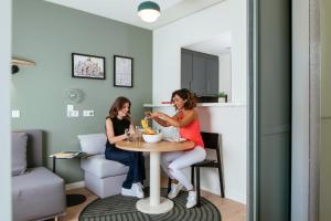 two women sitting at a table in a room at Aparthotel Adagio Muenchen City in Munich
