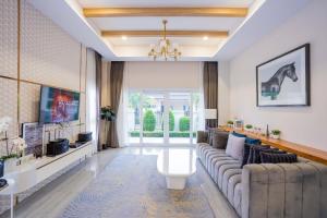 a living room with a couch and a tv at Beverly Hills Pool Villa Na Jomtien in Na Jomtien
