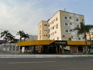 a building with a yellow awning on the side of a street at Afford Hotéis in Lages