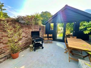 a patio with a brick wall and a house with a piano at Family Three Bedroom Home - Outbuilding Games Room - Walk to Town and Beach - Free Parking in Bournemouth