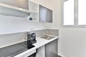 eine weiße Küche mit Spüle und Fenster in der Unterkunft Studio agréable et tout équipé - Montreuil in Montreuil