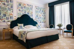 a bedroom with a large bed with a blue headboard at Hotel Le Negresco in Nice