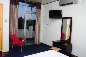 - une chambre avec une chaise rouge et un miroir dans l'établissement Sacred City Tourist Resort, à Anurâdhapura