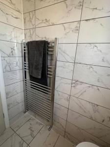 a white tiled bathroom with a shower with a towel at By Buildersbeds - Heaton House 2 Bedrooms in Havering atte Bower